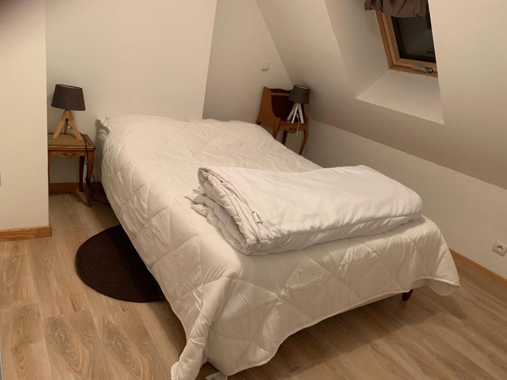 łóżko z białą pościelą w pokoju w obiekcie Logement Agréable récemment rénové à Aubusson w mieście Aubusson