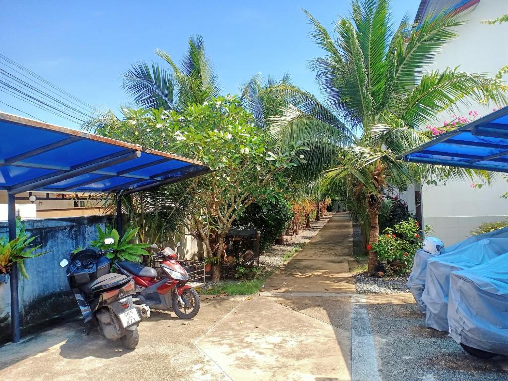 a motorcycle parked next to a house with palm trees at Coconoi Residence in Nai Harn Beach