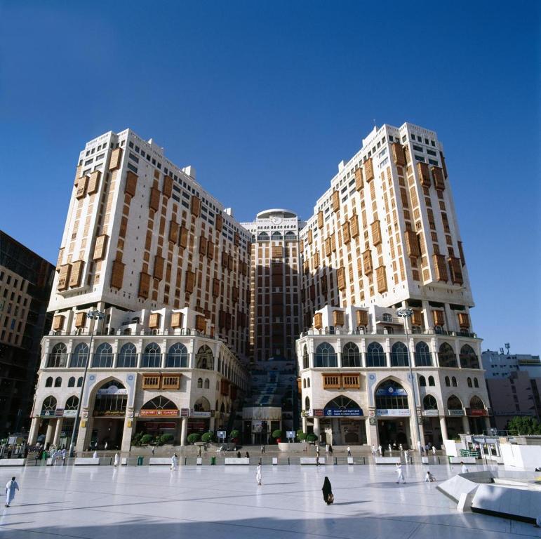 Deux grands bâtiments avec une place devant eux dans l'établissement Makkah Hotel, à La Mecque
