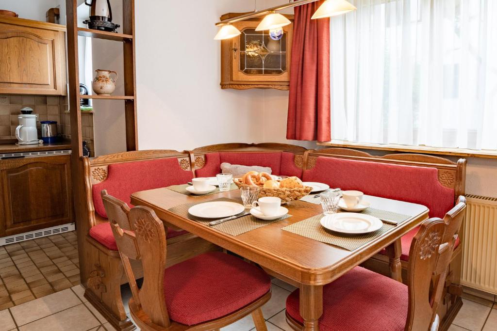 uma mesa de jantar com cadeiras vermelhas e uma mesa com uma tigela de comida em Bergsonne em Bad Hindelang