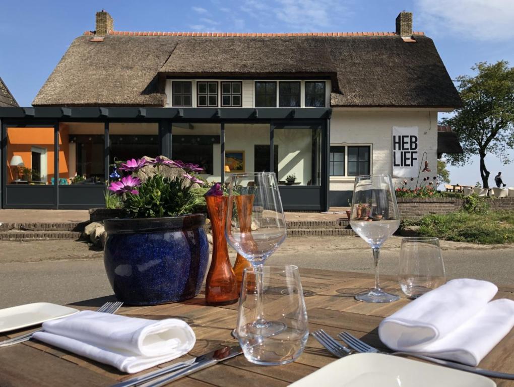 una mesa de madera con copas de vino y un jarrón con flores en Villa BlauwHemel Diever, en Diever