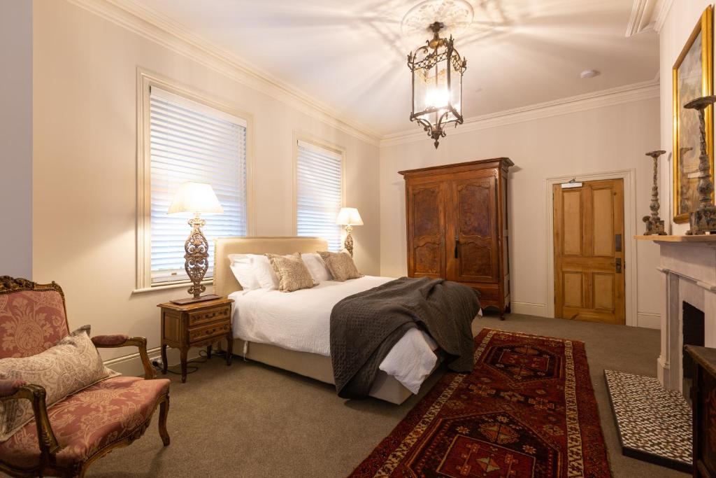 a bedroom with a bed and a chair and a fireplace at The Rivulet in Hobart