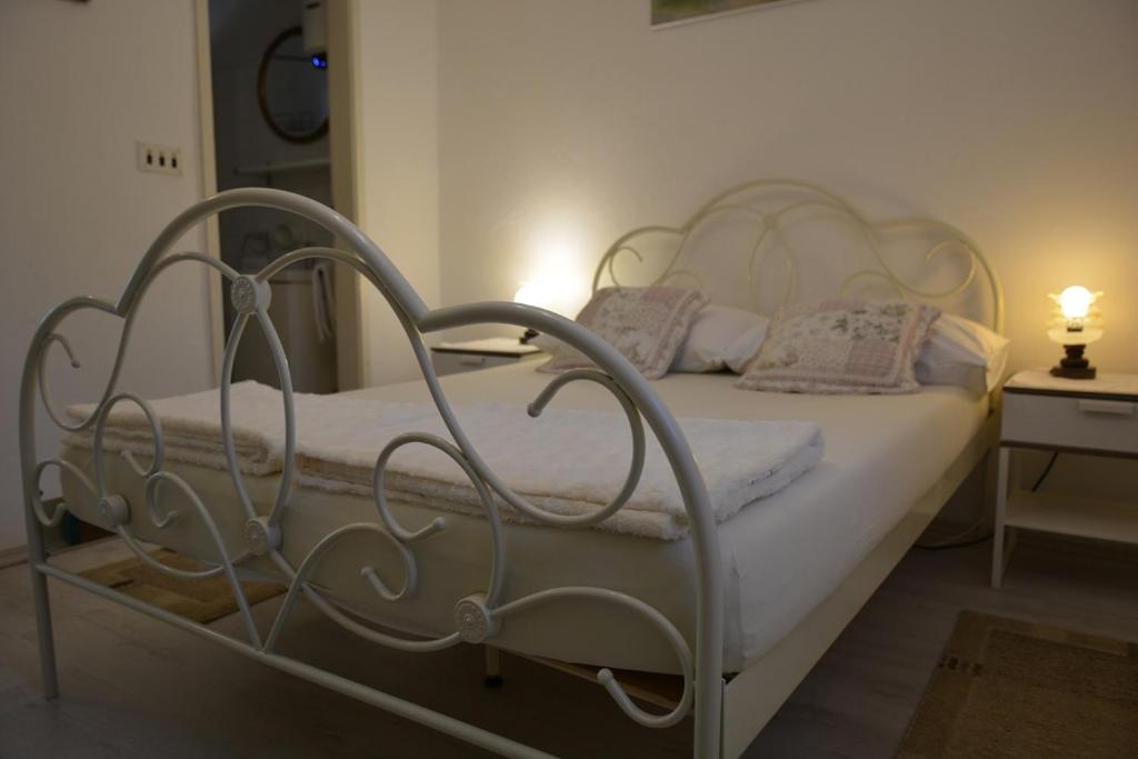 Una cama blanca con marco de metal en un dormitorio en Apartment Srsen en Kučište