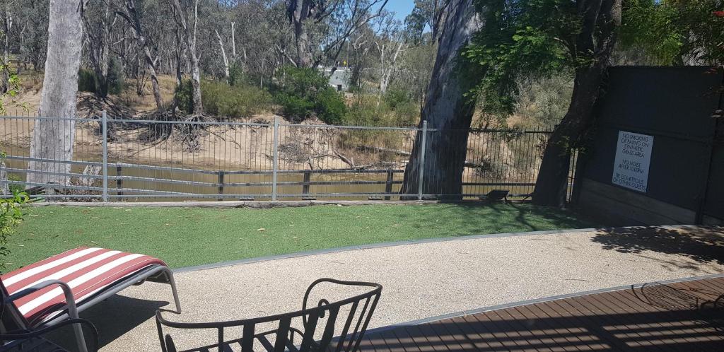 a bench in a park with a fence and grass at Adelphi Apartment 6 Riverview 2 BDRM or 6A King Studio Riverview both with balconies in Echuca