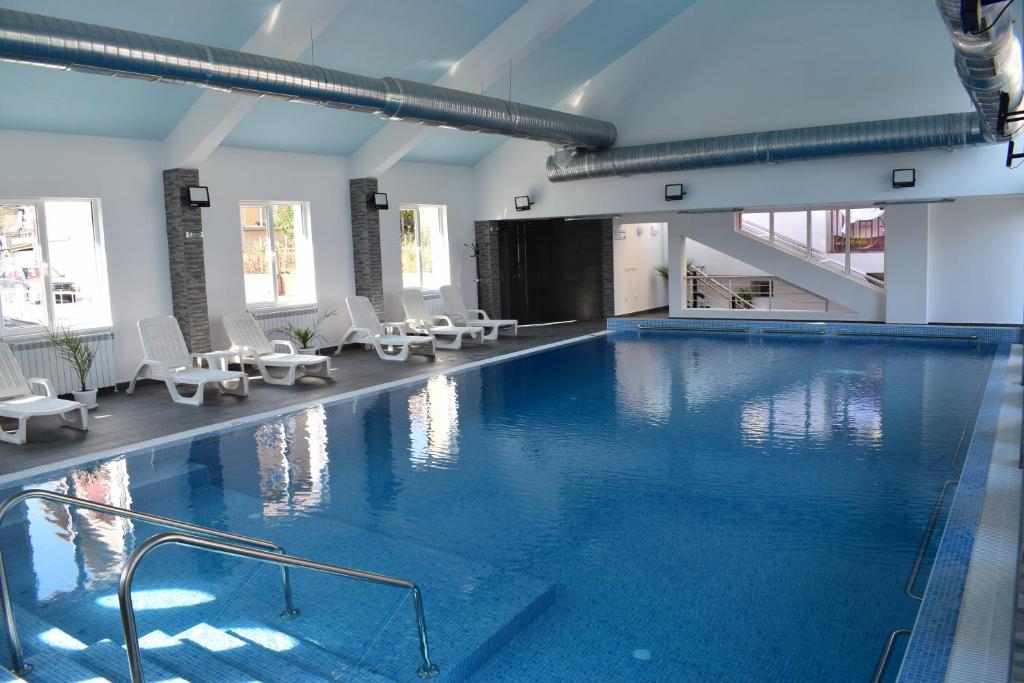 a large swimming pool with white chairs in a building at Tintyava Balneohotel in Varshets