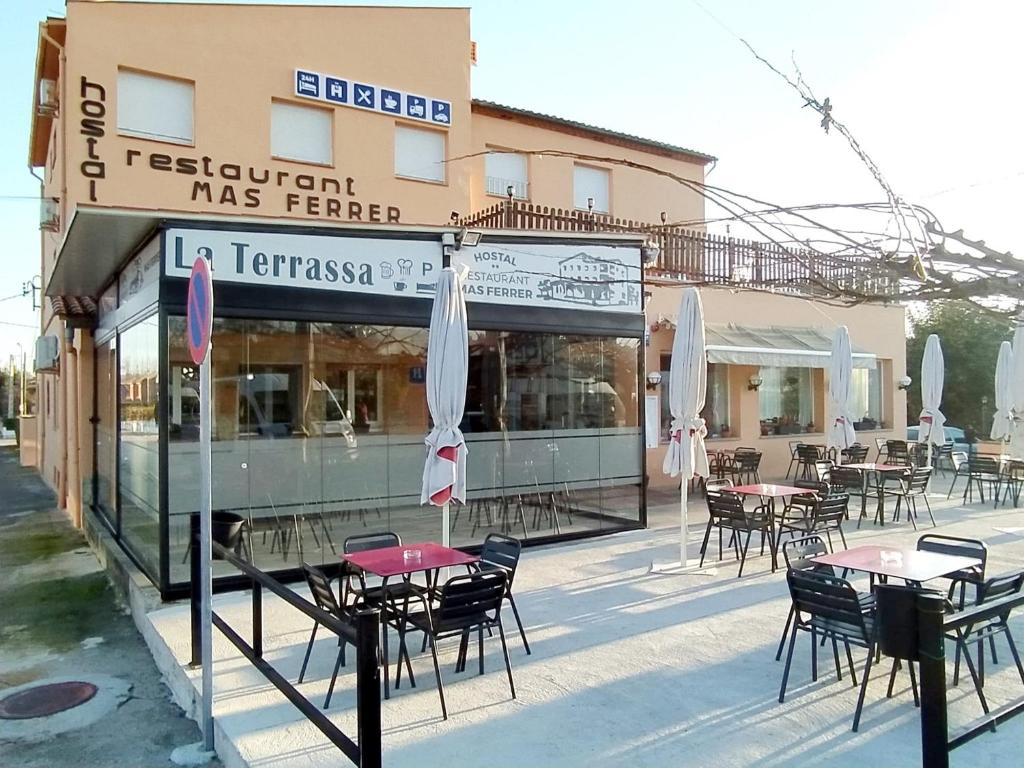 un restaurante con mesas y sillas frente a un edificio en Hostal Mas Ferrer, en Cornellá de Terri