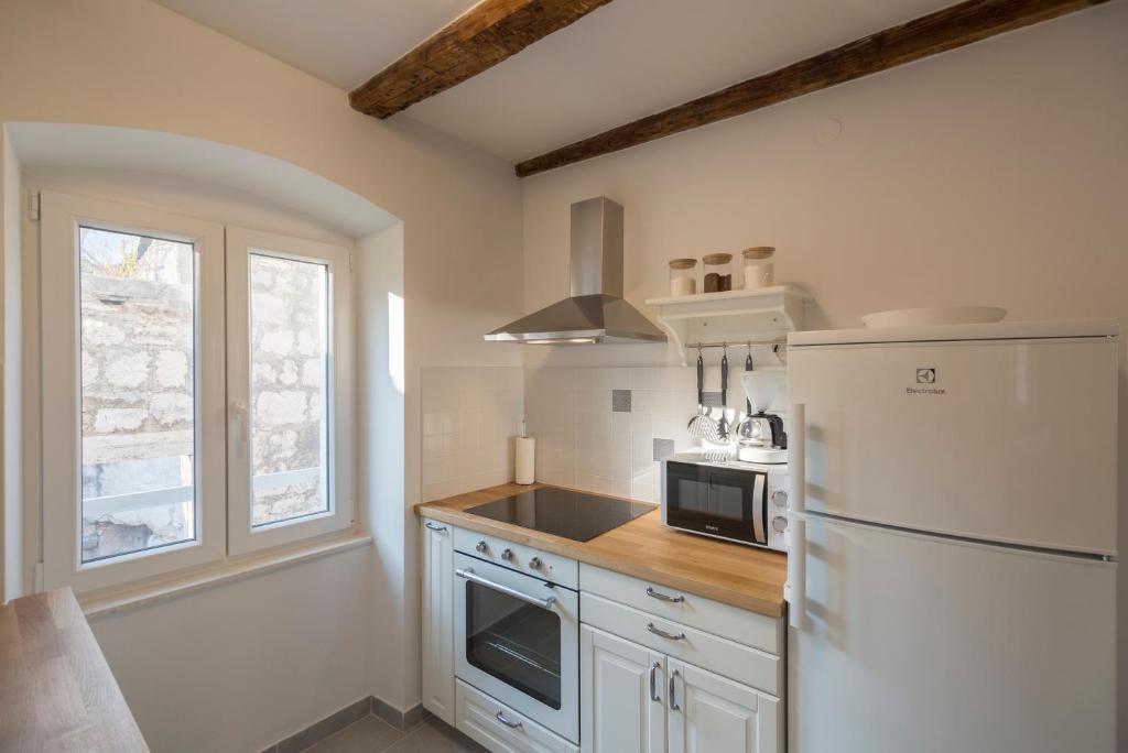 een keuken met een witte koelkast en een magnetron bij Apartments Bepi Komiza in Komiža