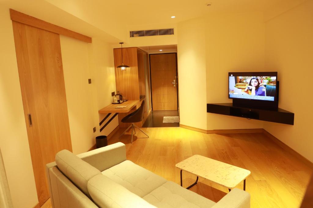 a living room with a couch and a tv on a wall at Manuelsons Malabar Palace in Kozhikode