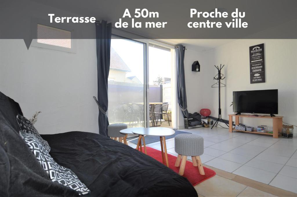 a bedroom with a bed and a tv and a table at Maisonnette avec terrasse à 50m de la plage in Luc-sur-Mer