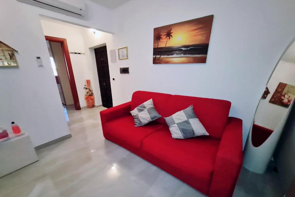 un divano rosso con due cuscini in soggiorno di Casa Vacanza Via Roma a San Giorgio Ionico