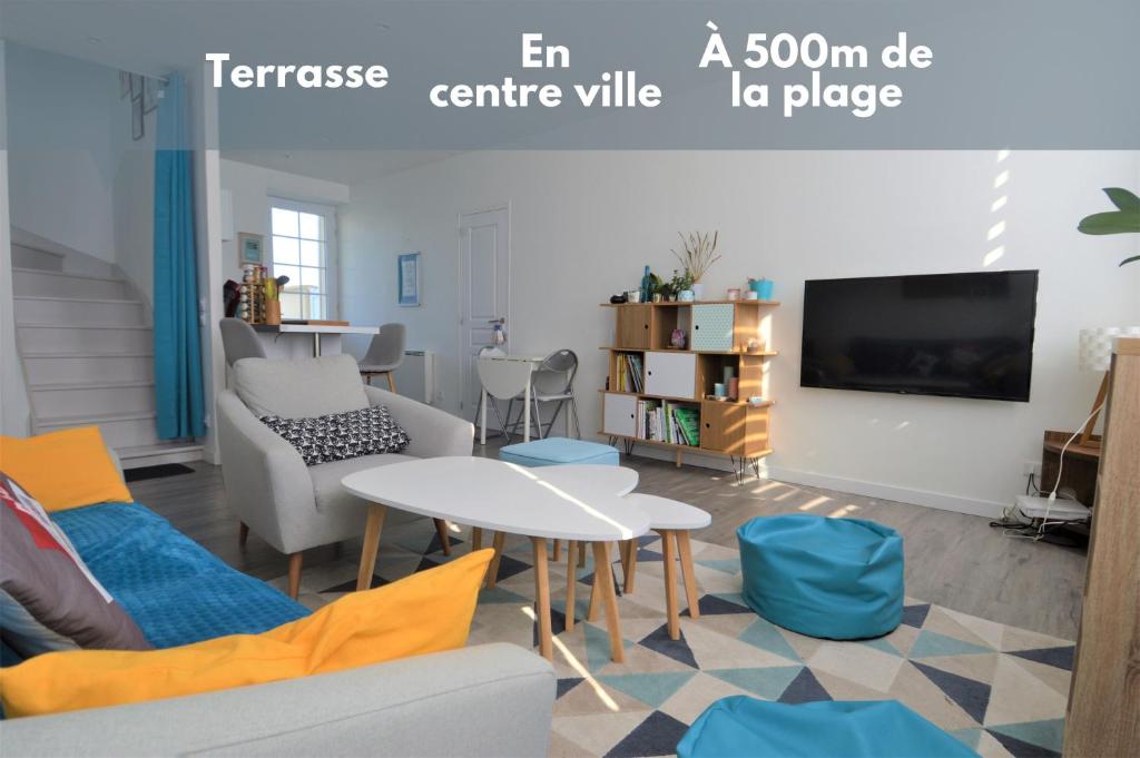 salon z kanapą i stołem w obiekcie Appartement moderne avec terrasse à 500m de la mer w mieście Courseulles-sur-Mer