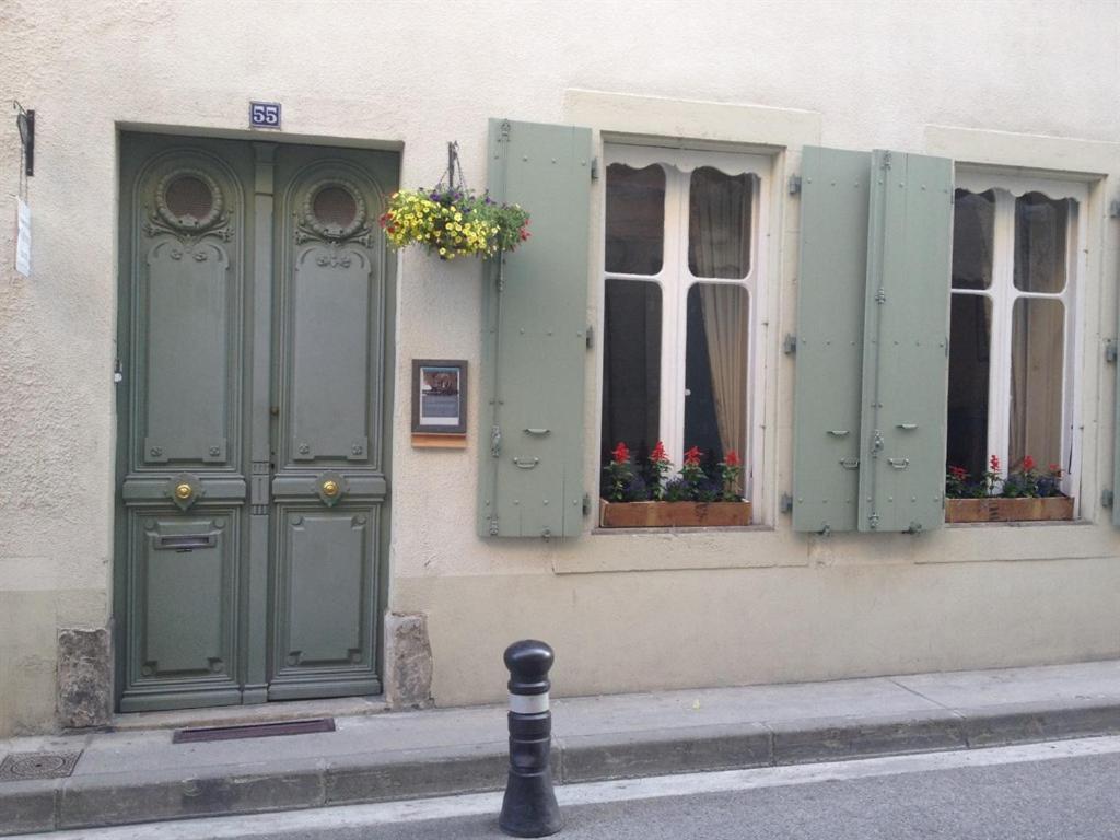 a building with green doors and windows with flowers at Maison Ville-Limoux in Limoux