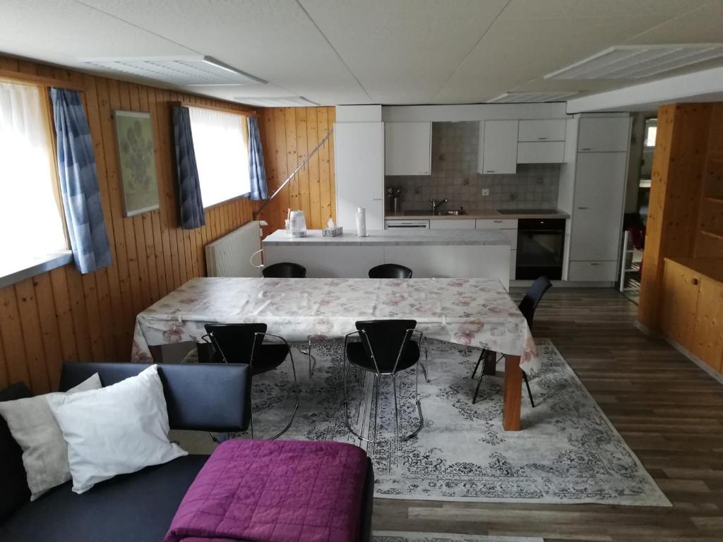 a living room with a table and chairs and a kitchen at Suretta2 in Splügen