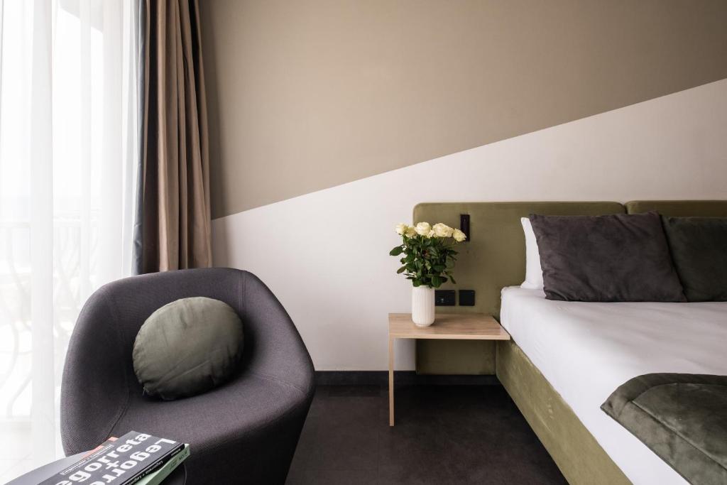 a bedroom with a bed and a chair and a table at Cavalieri Art Hotel in St. Julianʼs
