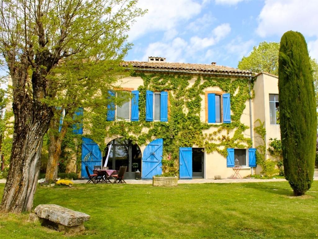 a house with blue shutters and a tree at Chambre D'hôte La Beaudine in Forcalquier