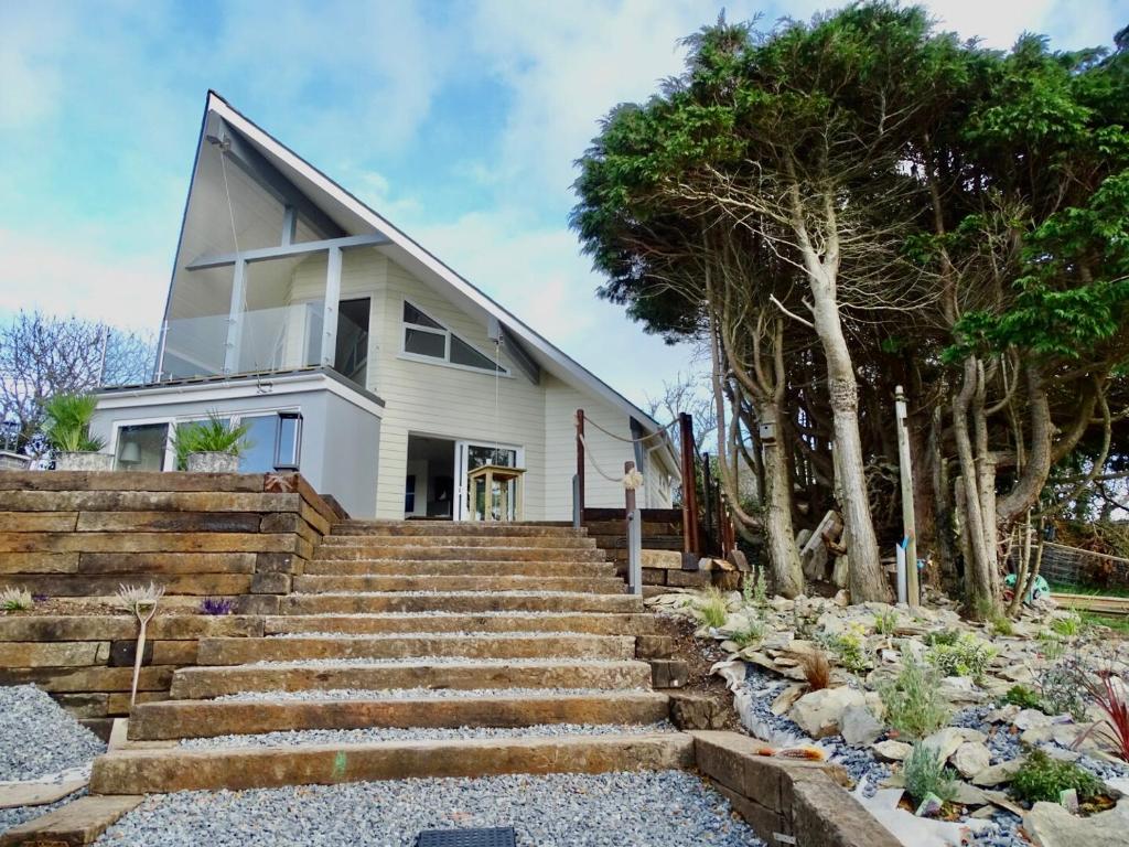 a white house with stairs and trees at The Kite, Upper Torrs View in Ilfracombe