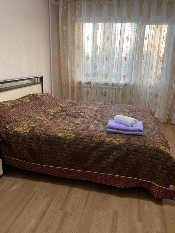 1 dormitorio con 1 cama con 2 toallas en Домашний уют, en Karagandá