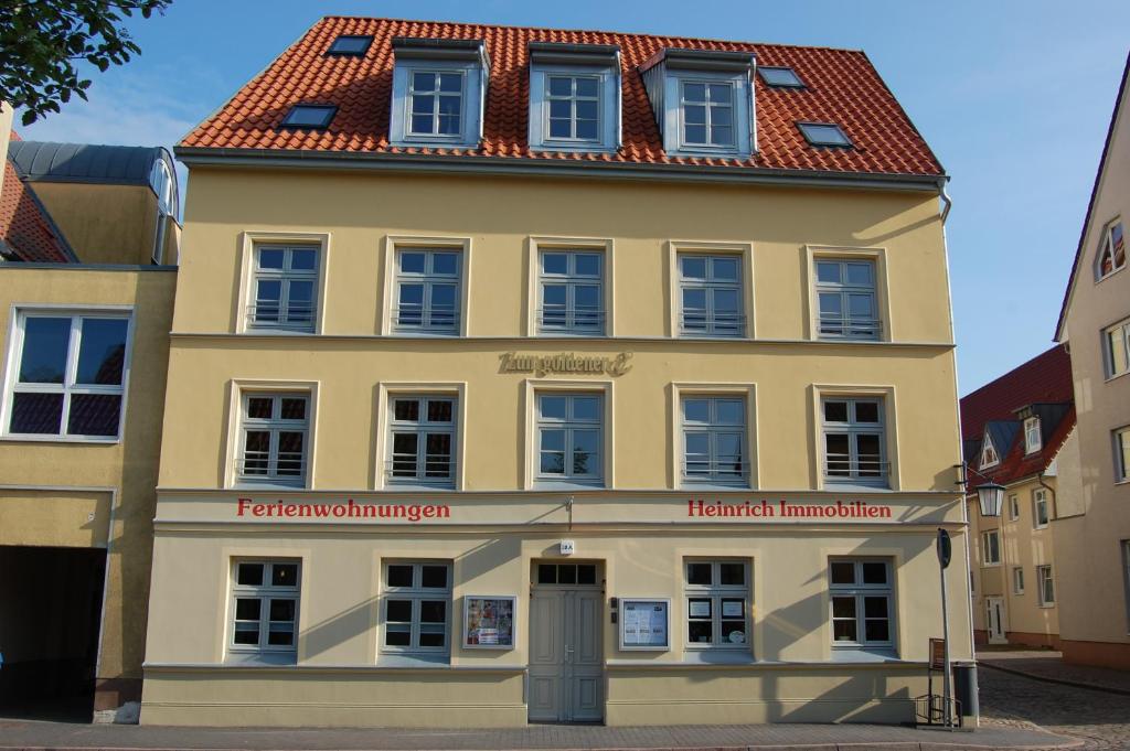 un grand bâtiment jaune avec un toit rouge dans l'établissement Zum Goldenen Anker, à Stralsund