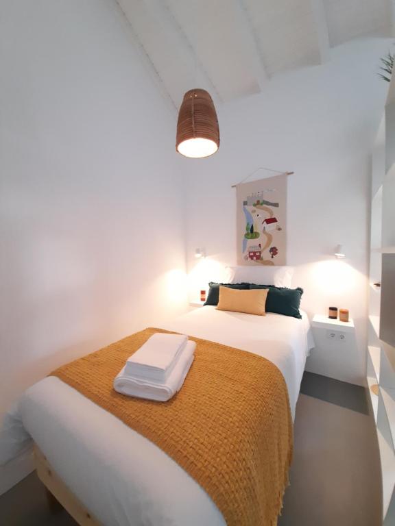 een witte slaapkamer met een bed met een gele deken bij Casa Vinte & Cinco Alojamento Local in Penha Garcia