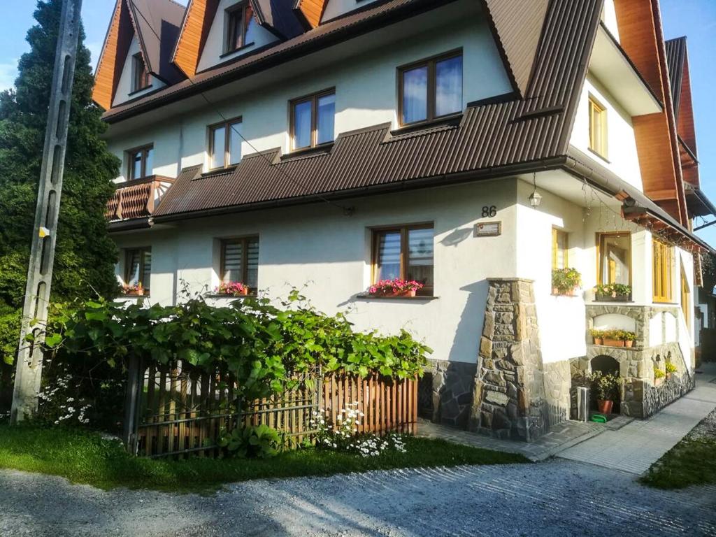 une maison blanche avec une clôture devant elle dans l'établissement Pokoje Gościnne Duda, à Białka Tatrzańska