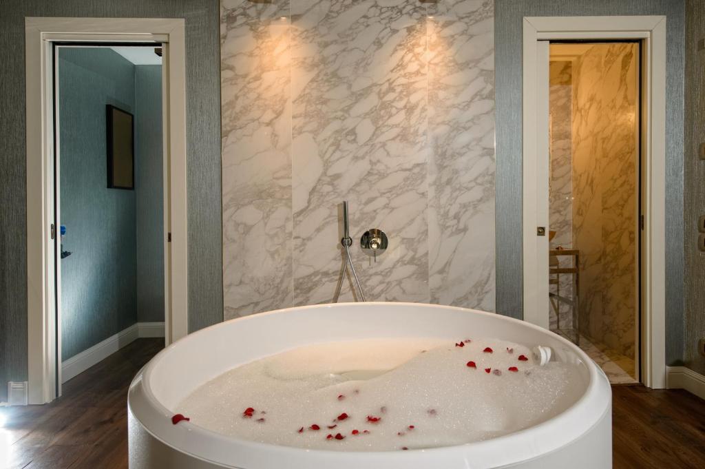a large white tub in a bathroom with marble walls at Palazzo Veneziano - Venice Collection in Venice