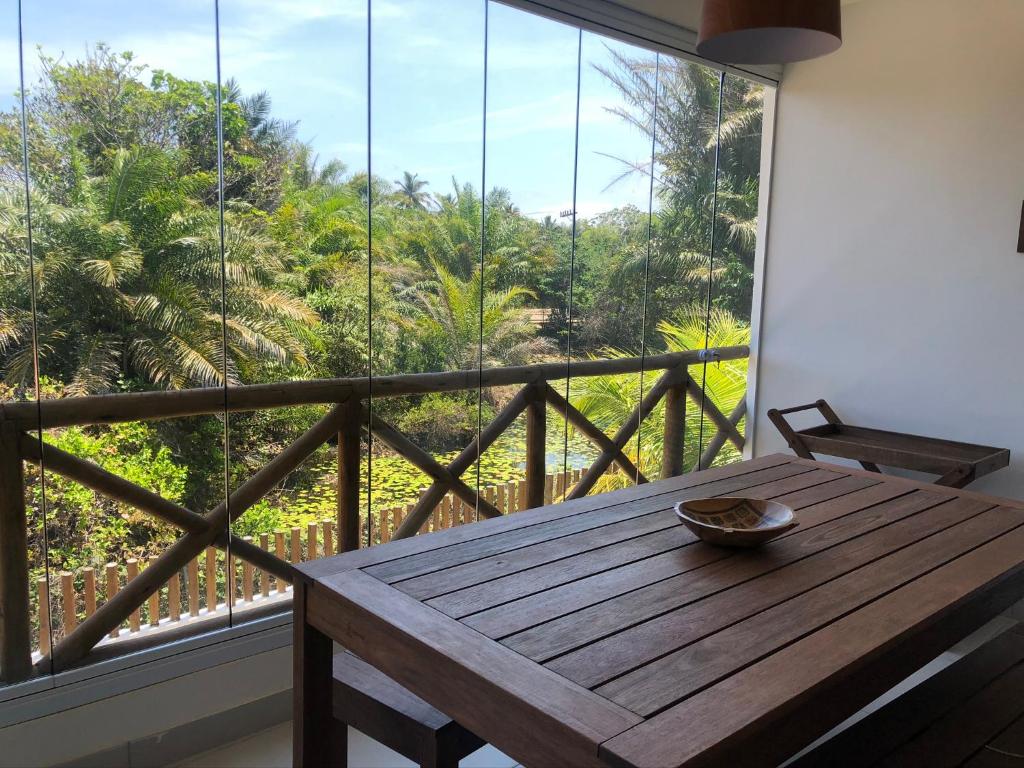 a wooden table in a room with a large window at Village em Imbassaí in Imbassai