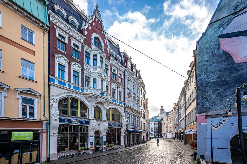 eine Stadtstraße mit Gebäuden und einer Person, die die Straße hinuntergeht in der Unterkunft Blue Bird Hostel in Riga Old Town in Riga