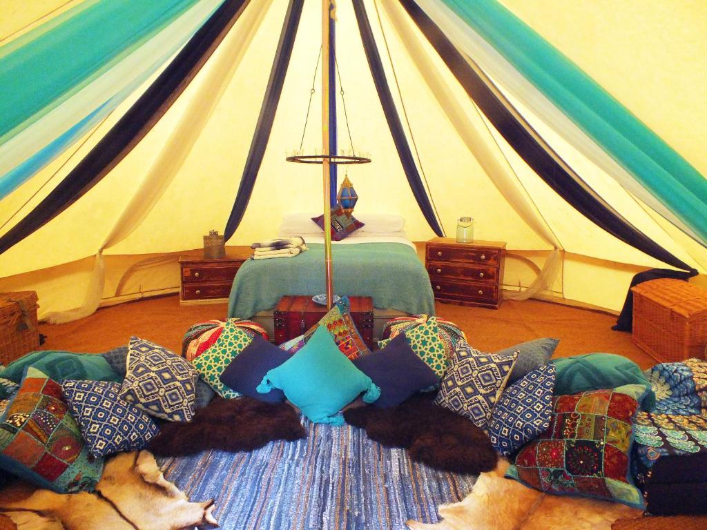 a tent with a dog laying on a couch with pillows at Hollington Park Glamping in Newbury