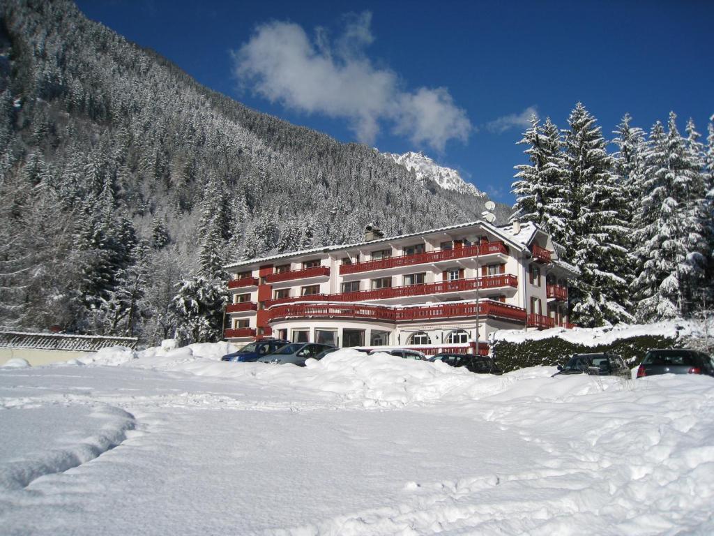 um grande edifício na neve em frente a uma montanha em Chalet Hôtel La Sapinière em Chamonix-Mont-Blanc