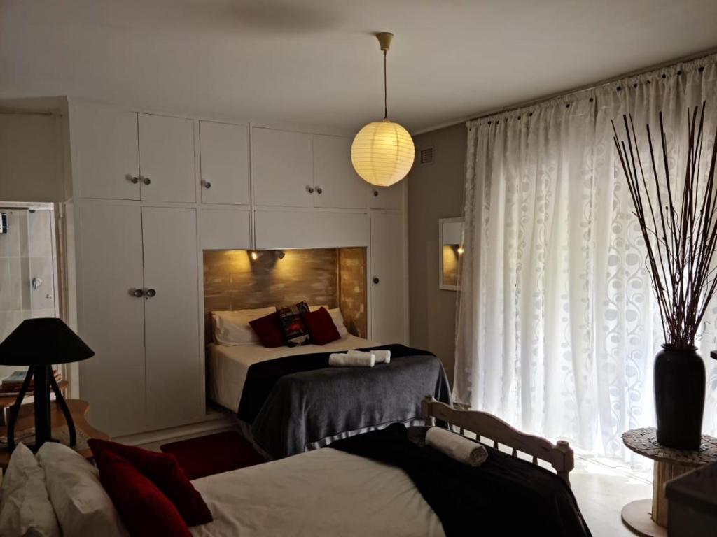 1 dormitorio con 2 camas y ventana grande en Angel's Corner, en Ciudad del Cabo
