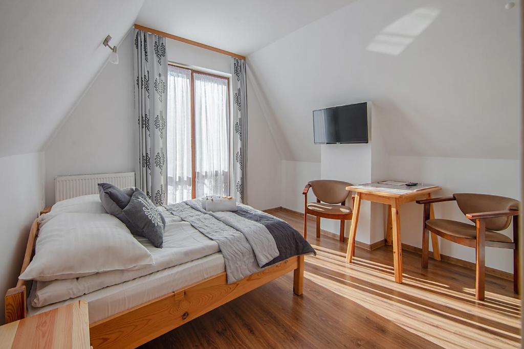 a bedroom with a bed and a table with chairs at Apartamenty Majerczyk in Zakopane