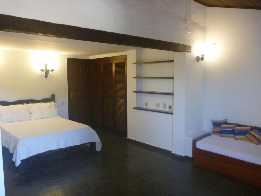 a bedroom with a bed and a bench in it at Espetacular Casa em João Fernandes e Vista Mar in Búzios