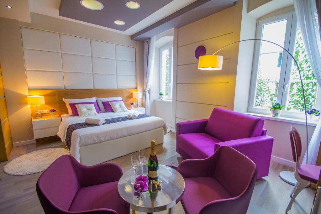 um quarto com uma cama, cadeiras roxas e uma mesa em Peninsula Luxury Rooms em Zadar