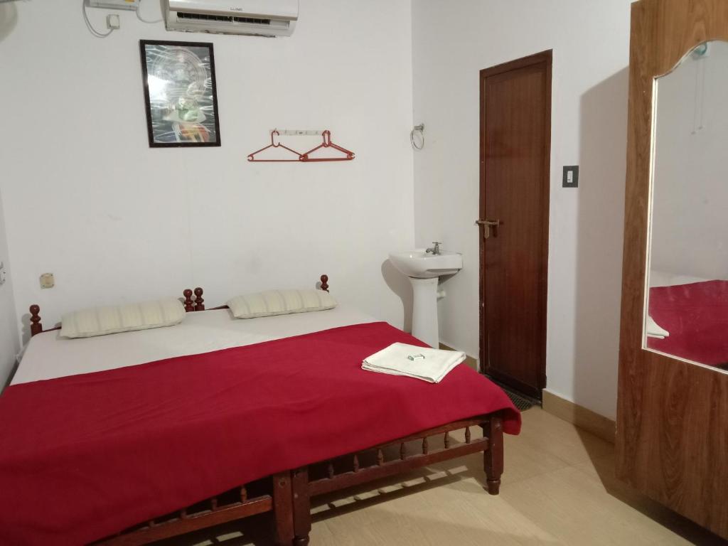 a bedroom with a bed with a red blanket and a sink at Cherai Ocean View Home in Cherai Beach