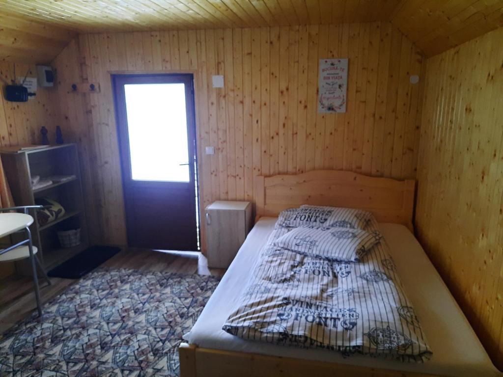 1 dormitorio con 1 cama en una habitación de madera en Casa La LEPE, en Roşia Montană