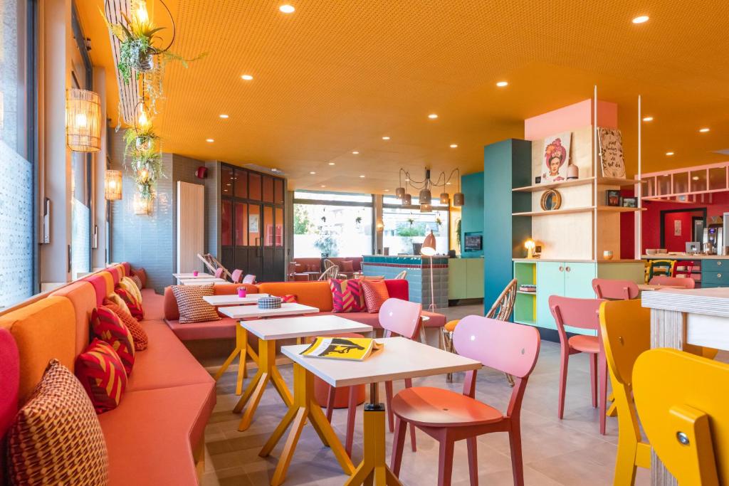 een restaurant met banken, tafels en stoelen bij PAUL & PIA - Welcome Home Hotel in Colmar