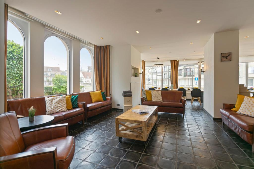 ein Wohnzimmer mit Sofas, Tischen und Fenstern in der Unterkunft Villa Renard in De Panne