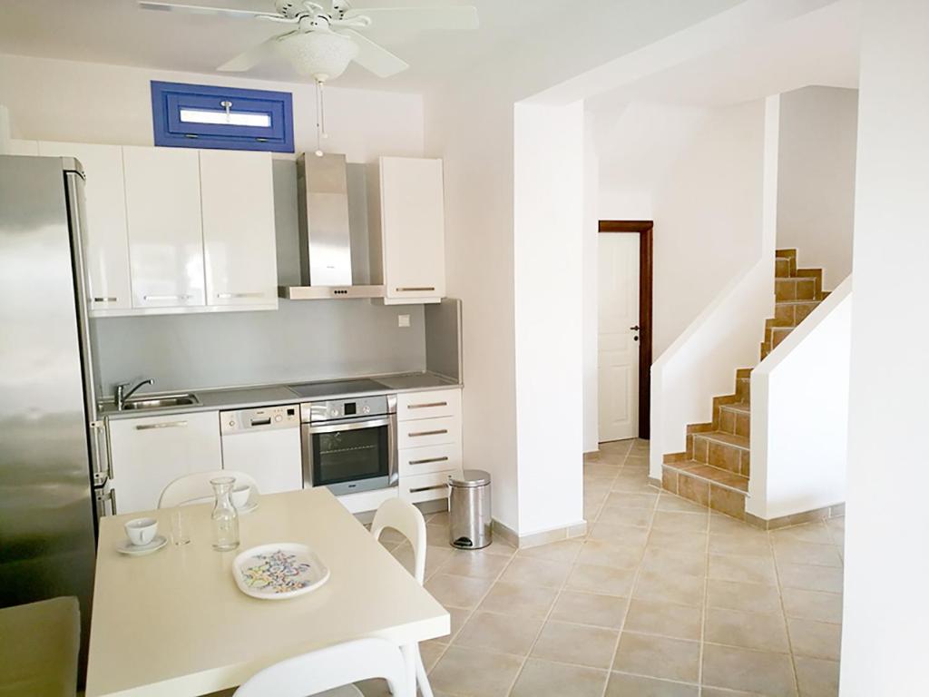 a kitchen with a table and a stove and a staircase at Olive Bay Hilltop Apartments Ammouliani in Ammouliani