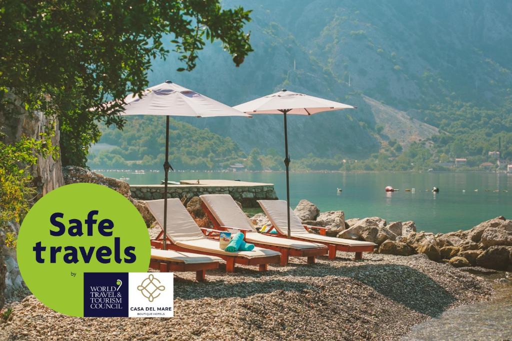 eine Gruppe von Liegestühlen und Sonnenschirmen am Strand in der Unterkunft Hotel Casa del Mare - Amfora in Kotor