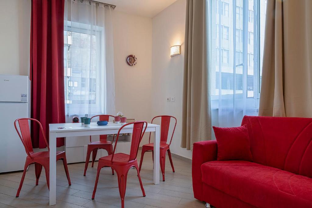 - un salon avec une table, des chaises et un canapé rouge dans l'établissement Casa Vermiglio al porto di Genova by Wonderful Italy, à Gênes