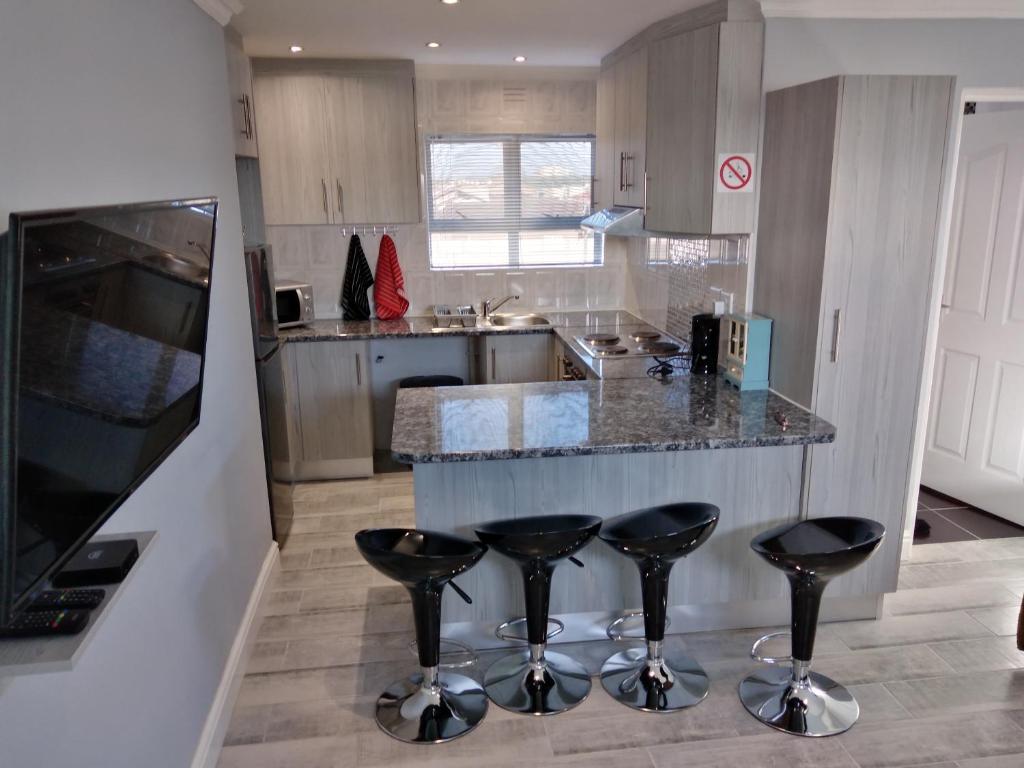 une cuisine avec deux tabourets de bar et un comptoir dans l'établissement Birds Holiday Accommodation 2, au Cap
