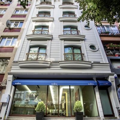 a tall white building with a blue awning in front of it at Ravvda Hotel in Istanbul