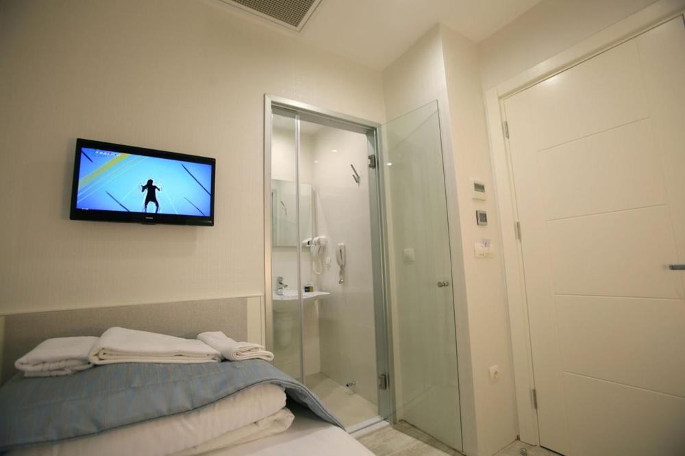 a bathroom with a television on a wall with a bed at Ravvda Hotel in Istanbul