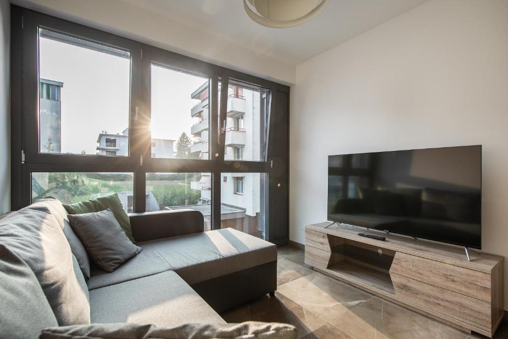 ein Wohnzimmer mit einem Sofa und einem Flachbild-TV in der Unterkunft Lucy by Quokka 360 - a stone's throw from the station in Massagno