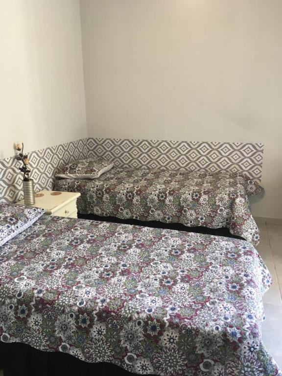 a bedroom with two beds and a table with a bedspread at Quarto Paulínia 2 in Paulínia