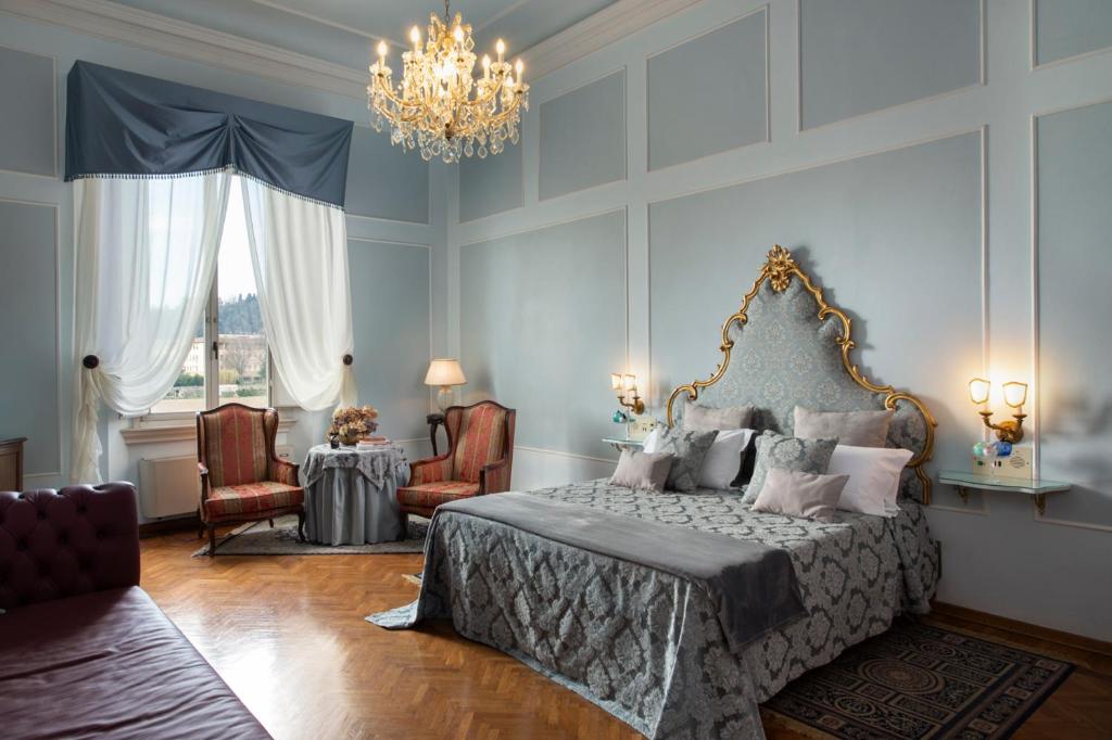 a bedroom with a bed and a table and a chandelier at Hotel Principe in Florence