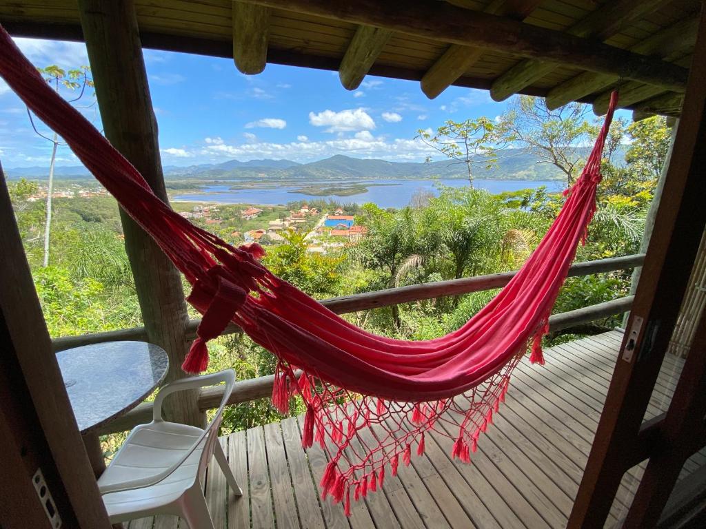 een hangmat op een veranda met uitzicht op een meer bij Pousada Villa São Pedro in Garopaba