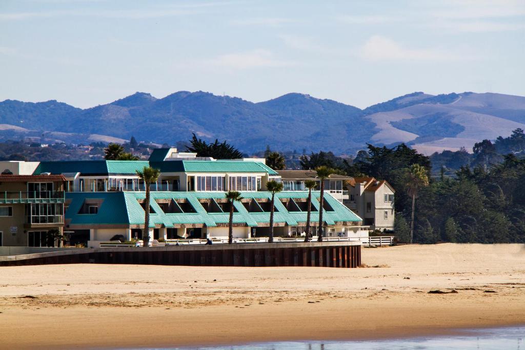 a resort on the beach with mountains in the background at SeaVenture Beach Hotel in Pismo Beach
