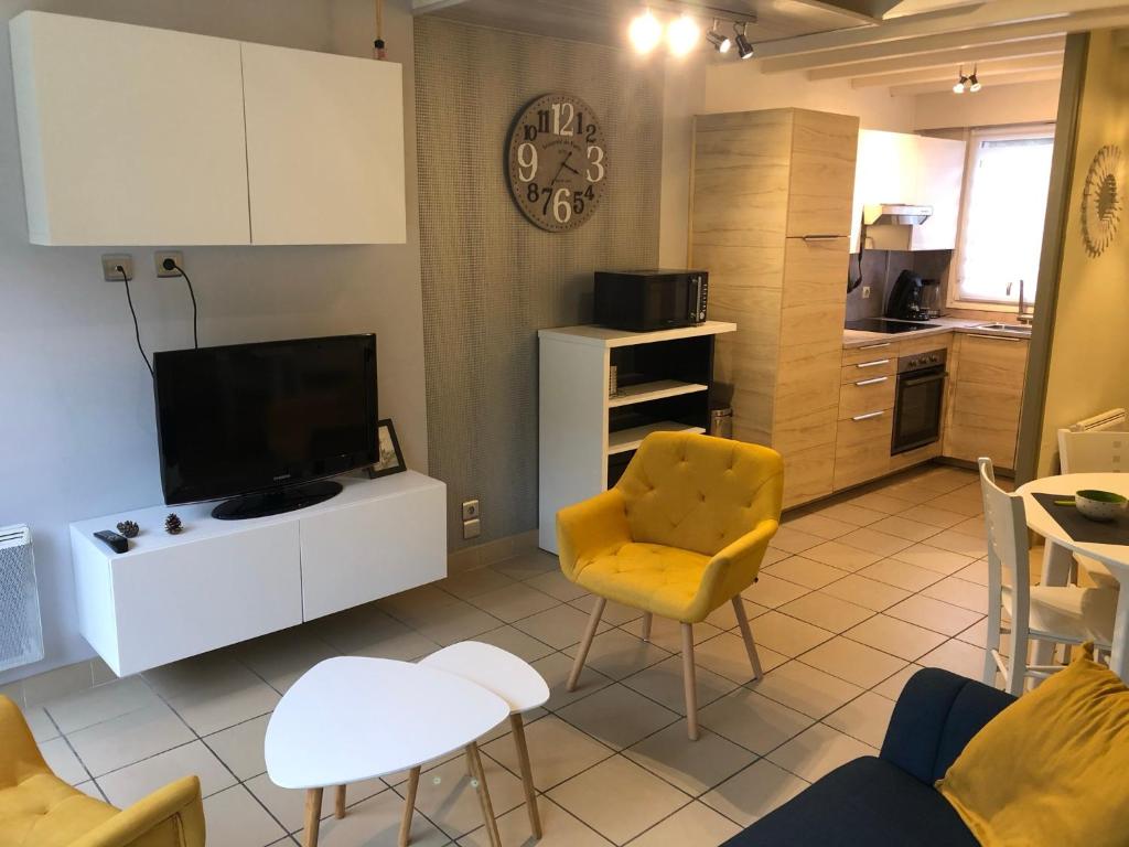 d'un salon avec une télévision et une chaise jaune. dans l'établissement Cottage Opale, à Stella-Plage