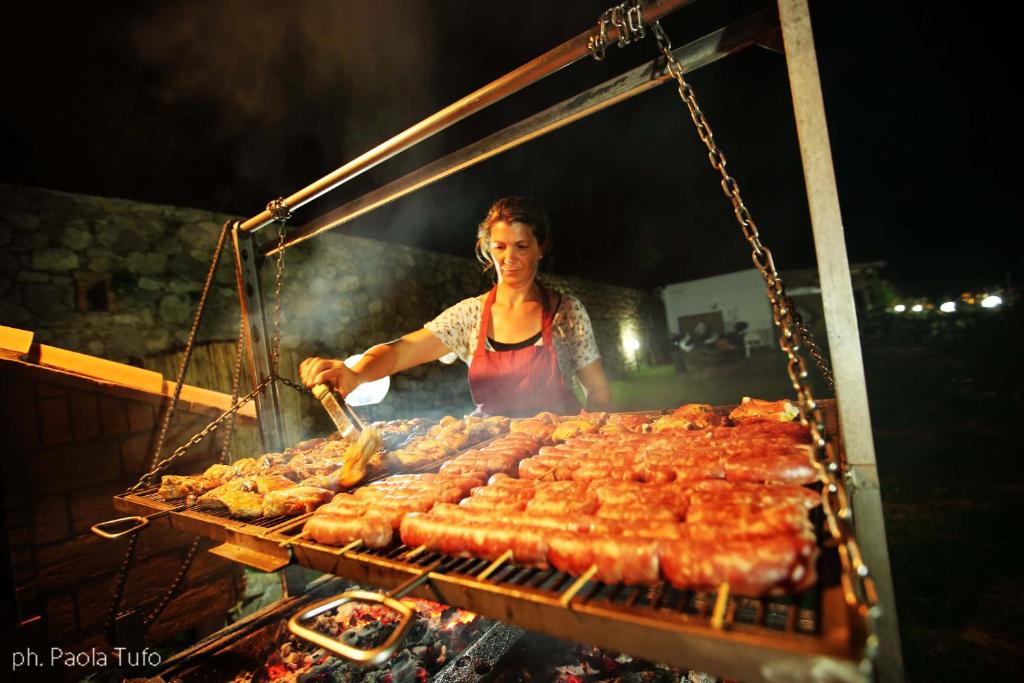 a woman is cooking meat on a grill at Agriturismo del Sole in Anacapri